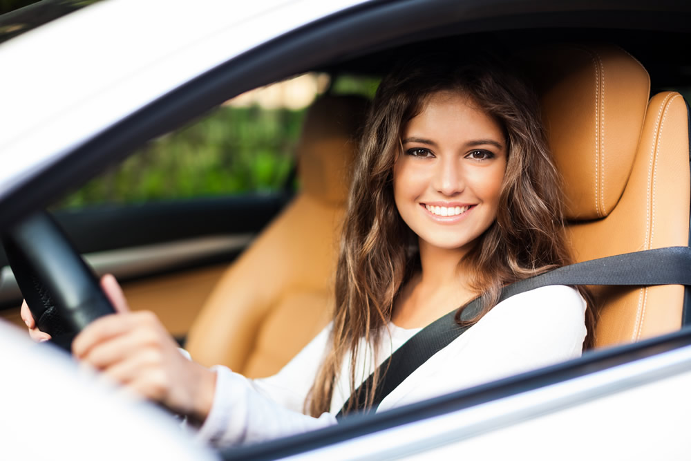 Smiling girl in white car looking out passenger window