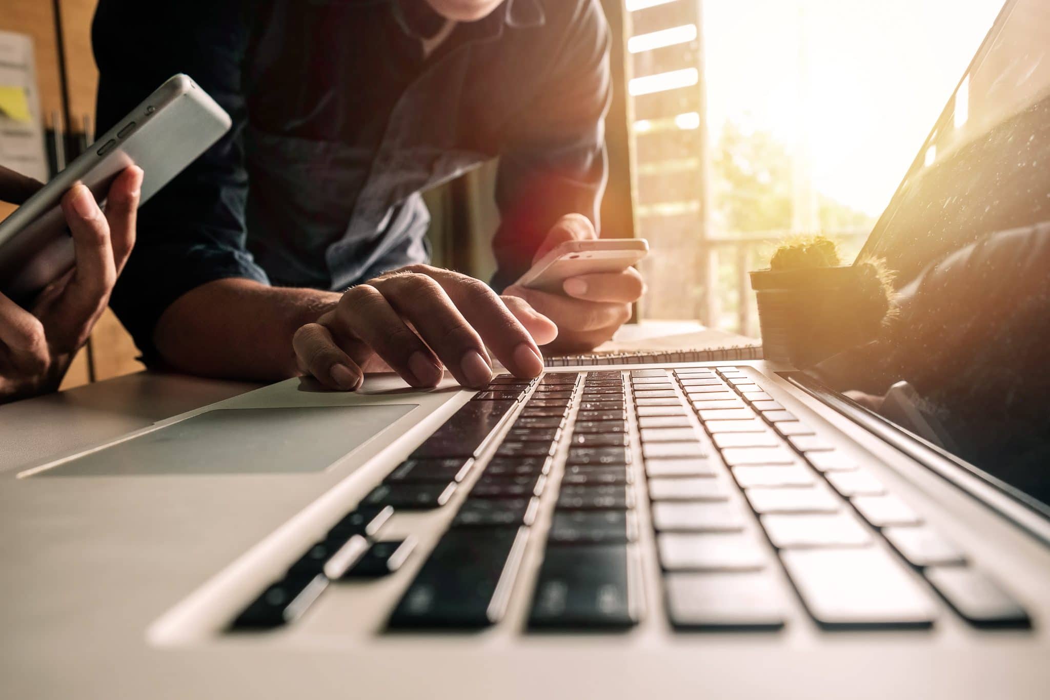 Laptop keyboard with people typing in an office environment